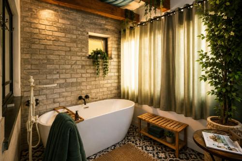 a bathroom with a white tub and a brick wall at סתיו בגולן in Qasrîne
