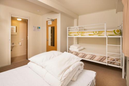 a bedroom with two bunk beds with white sheets at Ski Club of Victoria - Kandahar Lodge in Mount Buller