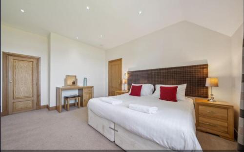 a bedroom with a large white bed with red pillows at No 15 Lomond Castle in Balloch
