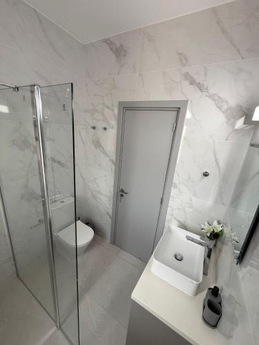 a white bathroom with a shower and a sink at Villa Artemis - 150m from Kapparis Beach in Paralimni