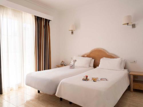 a bedroom with a large white bed with toys on it at Ona Village Cala d'Or in Cala d´Or