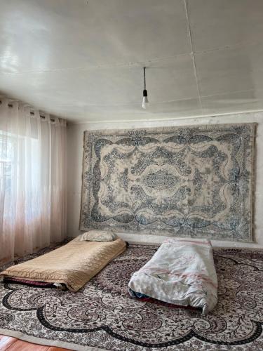 a bedroom with two beds and a tapestry on the wall at Ademi Art in Kyzart