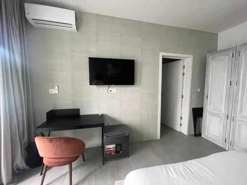 a bedroom with a desk and a television on a wall at Résidence Gabriel in Sali Nianiaral