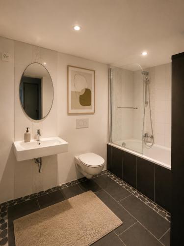 a bathroom with a toilet and a sink and a tub at Art Residence, Beat Schild in Brienz