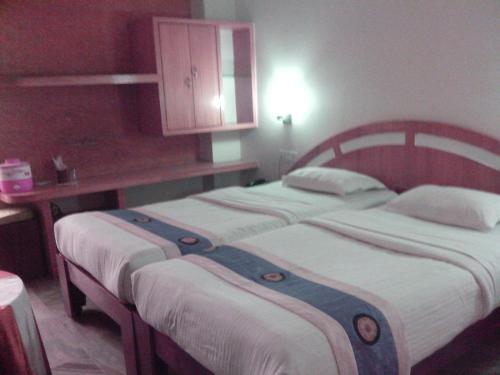a bedroom with two beds and a cabinet at Hotel Mahalaxmi Indo Myanmar in Guwahati