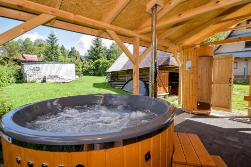 a hot tub in a backyard with a wooden roof at U Stocha - Jacuzzi & sauna - dom dla 13 osób in Poronin