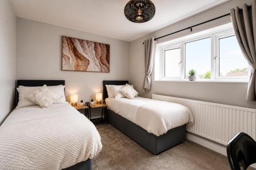 two beds in a room with two windows at Beautiful Abode in The Bath Cotswolds in Frome