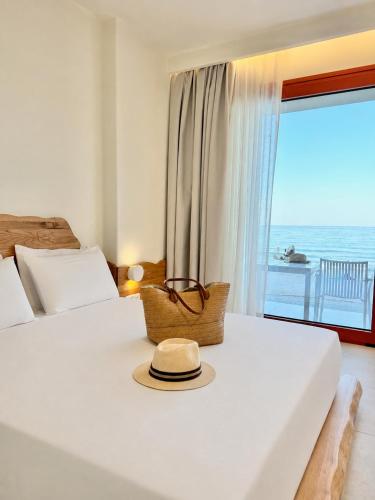 a hat sitting on a bed in a room with a window at Xanthos Beachfront Suites in Potamiá