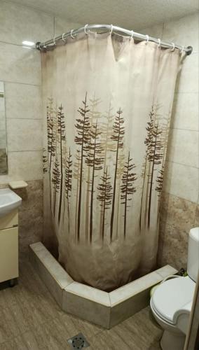 a bathroom with a shower curtain with trees on it at Апартаменты in Jermuk