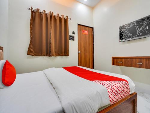 a bedroom with a bed with a red and white blanket at Hotel O R.S in Nagpur
