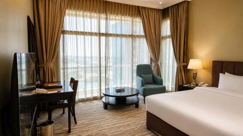 a hotel room with a bed and a desk and a window at Oryx Hotel in Abu Dhabi