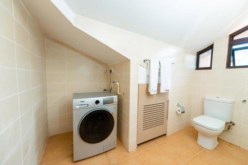 a bathroom with a washing machine and a toilet at Heri Heights Hotel Apartments, SureStay Collection by Best Western in Nairobi