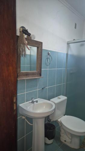 a bathroom with a sink and a toilet and a mirror at POUSADA SERRA DA CANASTRA in Delfinópolis