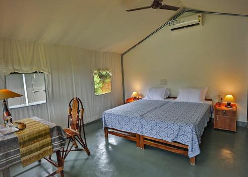 a bedroom with a bed and a table and a chair at Birds Murmur Camp, Thattekkad in Cochin