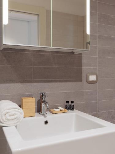a bathroom with a white sink and a mirror at Portopiccolo Apartments Deluxe in Sistiana
