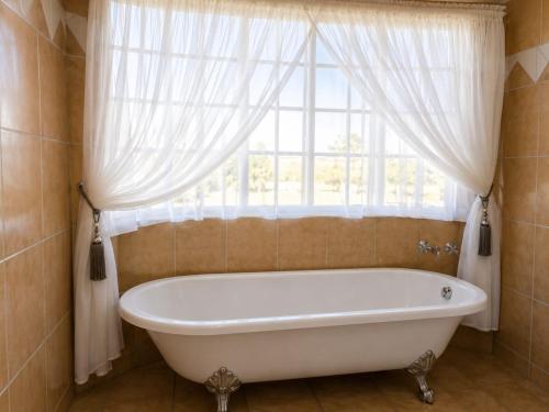 a bath tub in a bathroom with a window at Anna Boeremeisie Guesthouse in Benoni