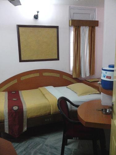 a bedroom with two beds and a desk and a table at Hotel Mahalaxmi Indo Myanmar in Guwahati