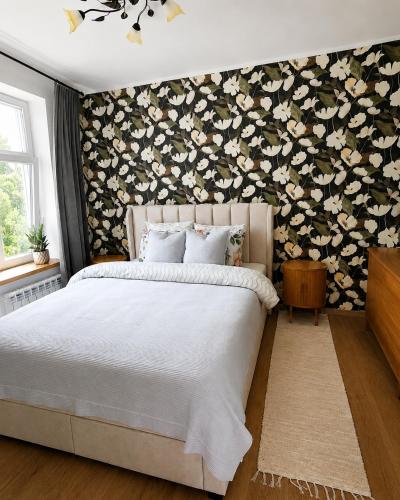 a bedroom with a bed with a floral accent wall at Katariina allee korter in Võru