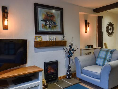 a living room with a couch and a tv and a fireplace at Byways in Cartmel