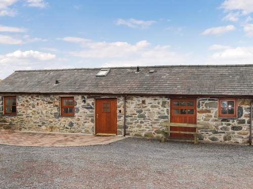 a stone building with two doors and a roof at Beudy Newydd - Uk50959 in Llanllechid