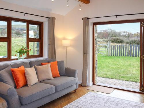 a living room with a couch and a sliding glass door at Beudy Newydd - Uk50959 in Llanllechid