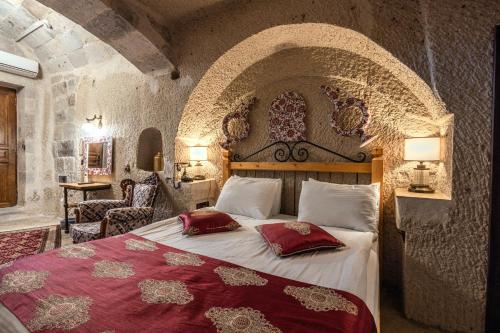 a bedroom with a large bed with red pillows at Aren Cave Hotel And Art Gallery in Göreme