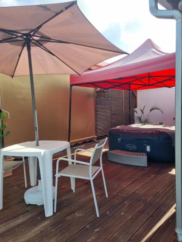 a table and a chair and an umbrella on a deck at Charmant studio d'invité - Baie-Mahault in Baie-Mahault
