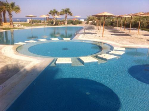 a large swimming pool with chairs and umbrellas at Athinas Art House in Kolymbia