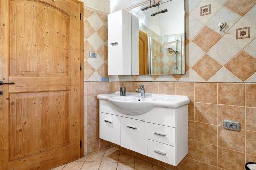 a bathroom with a sink and a mirror and a door at Agritur Maso Bornie in Grauno