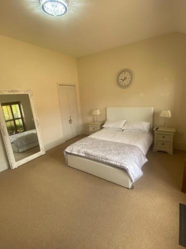 a bedroom with a bed and a clock on the wall at Lavender Cottage in Long Bennington