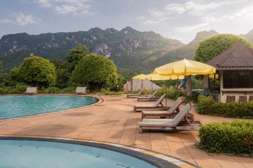 a group of chairs and umbrellas next to a pool at Pung-Waan Resort in Sai Yok