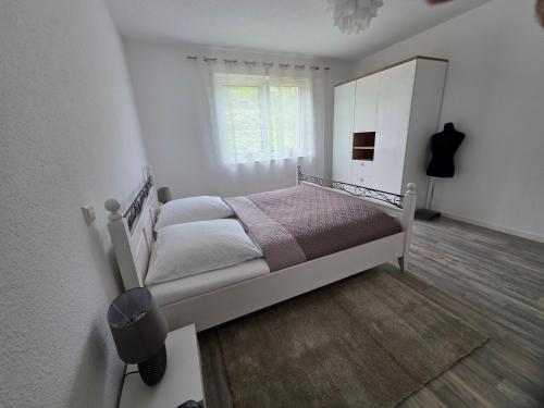 a white bedroom with a bed and a window at Quiet Place in Achern