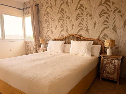 a bedroom with a bed with white sheets and a wallpaper at Finca Sonrisa in Alhaurín el Grande