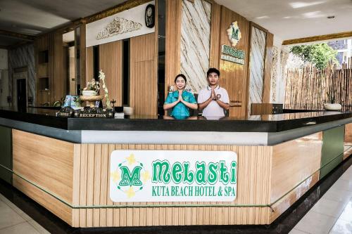 two people standing at a counter in a restaurant at Melasti Kuta Beach Hotel & Spa in Kuta