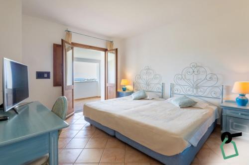 a bedroom with a bed and a desk and a television at Hotiday Baja Sardinia Saline in Baja Sardinia