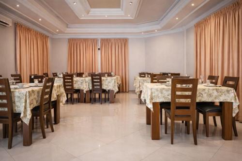 a dining room with tables and chairs and curtains at Hotel Murex in Brazzaville