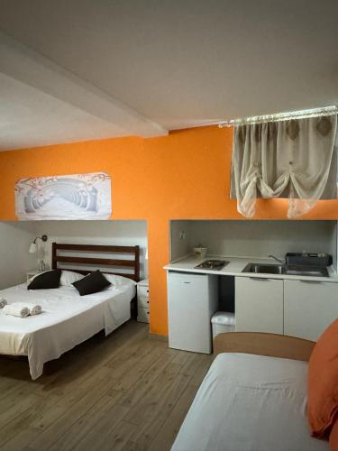 a bedroom with two beds and an orange wall at B&B Villa Jasiga in Fregene