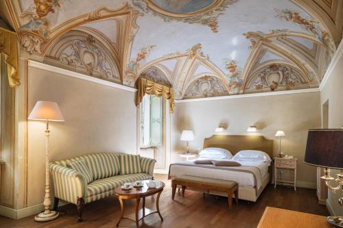 a bedroom with a king sized bed and a couch at Posta Donini 1579 - UNA Esperienze in San Martino in Campo
