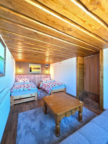 a room with two beds and a wooden ceiling at Ubytovanie u Richtára in Klokoč