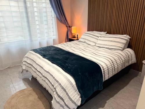 a bedroom with a bed with a striped blanket and a window at WN Apartments in Lusaka
