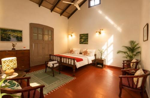 a bedroom with a bed and a table and chairs at amã Stays & Trails - Fairholme Bungalow ,Yercaud in Yercaud