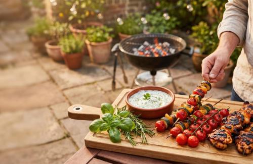 a person preparing food on a cutting board next to a grill at amã Stays & Trails - Fairholme Bungalow ,Yercaud in Yercaud