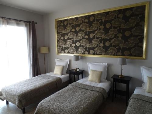 a room with three beds and a painting on the wall at Maison du Lac in Les Angles Gard