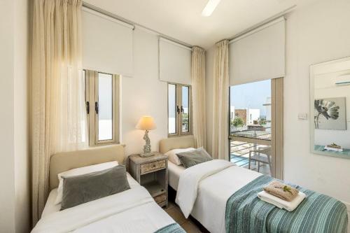 two beds in a room with a window at Fig Tree Beach villa Three in Protaras