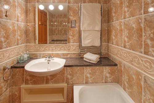 uma casa de banho com um lavatório e uma banheira em The Dunstanburgh Castle Hotel em Embleton