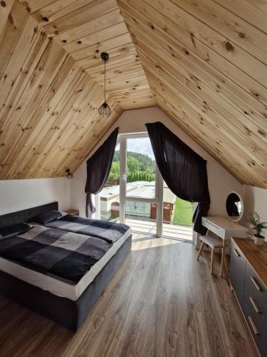 a bedroom with a large bed and wooden ceilings at Sosnowa Polana Rusinowo in Rusinowo