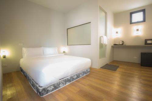 a large white bed in a room with wooden floors at Glur Central Pratunam in Bangkok