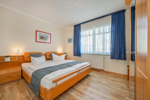 a bedroom with a large bed with blue curtains at Ferienwohnung Koralle in Koserow