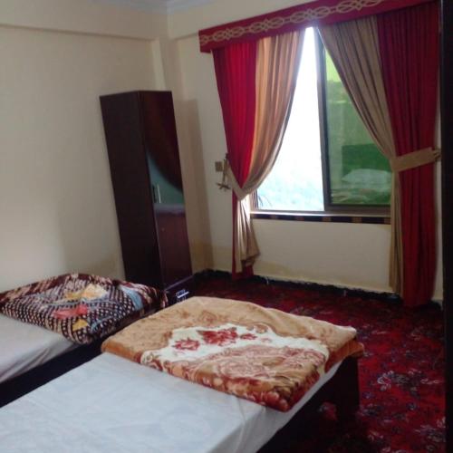a hotel room with two beds and a window at UK Residencia in Murree