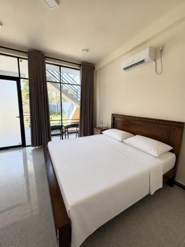 a bedroom with a large white bed and large windows at SIORA Retreat in Dambulla